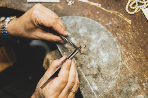 istock Jeweler working in his workshop placing a gem on a gold ring 1440967902