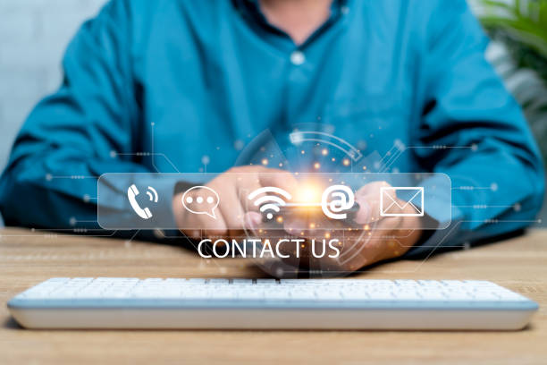 istock Contact us or the Customer support hotline people connect. Businessman using a smartphone and on a virtual screen on contact icons and computer keyboard on table 1440967932