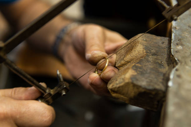 istock Jeweler working in his workshop cutting a gold ring with a saw 1440968086