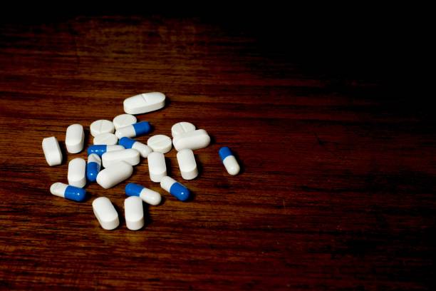 istock Pile of white and blue pills on a brown background 1440969149