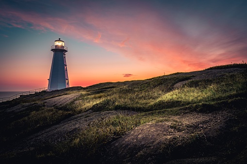 A breathtaking view of Cape Spear Lighthouse on colorful sky background during sunrise