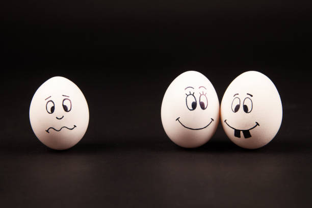 istock Closeup of three white eggs with funny and happy faces on a black surface 1440972701