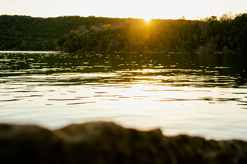 A scenic view of the Possum Kingdom lake reflecting the sun rays with green lush forests in the background