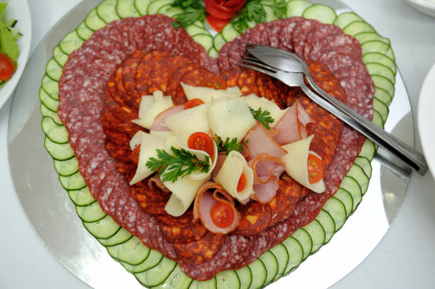 istock Heart-shaped sausage plate decorated with cheese, cherry tomatoes and ham. 1440973587