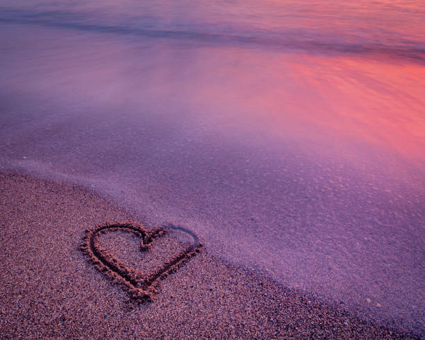 istock Heart carved into sand on a seashore at sunset 1440974614