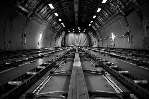 A grayscale shot of the cargo hold of an airplane