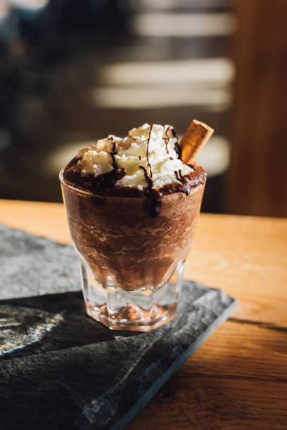 istock Hot chocolate topped with whipped cream, chocolate drizzle, cinnamon stick on wood table 1440976137