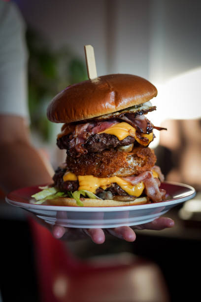 istock Vertical closeup of the hand holding a plate with burger. 1440976169