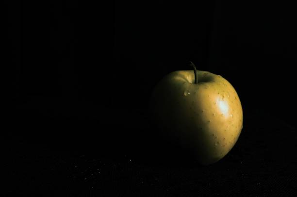 A closeup of a green apple with a black background