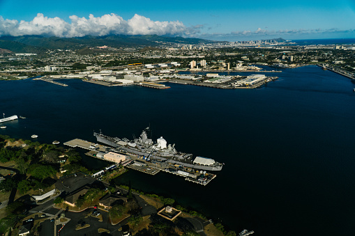 Honolulu, HI / USA – February 25, 2021: Aerial view of Pearl Harbour National Memorial and Battleship Missouri Memorial in pacific ocean, Honolulu, Hawaii Islands, USA.\n\nThe USS Arizona Memorial, built in 1962 at Pearl Harbor in Honolulu, Hawaii, marks the resting pease of sailors and Marines killed on USS Arizona Battleship during the Attack on Pearl Harbor on December 7, 1941.\n\nUSS Missouri (BB-63) is an Iowa-class battleship and was the third ship of the United States Navy to be named after the U.S. state of Missouri. Missouri was the last battleship commissioned in 1944 by the United States.