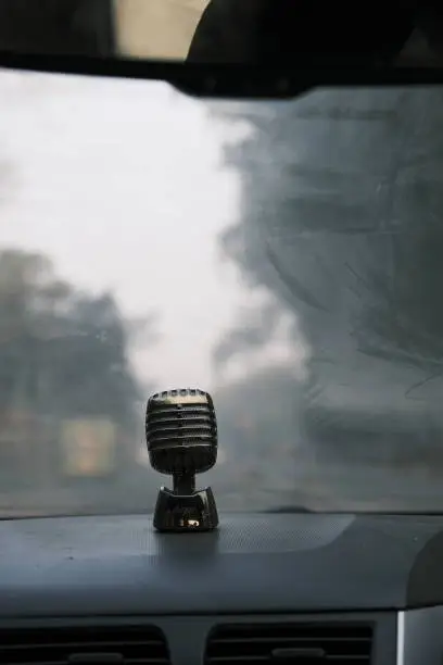 A mic air freshener bobblehead on a car dashboard