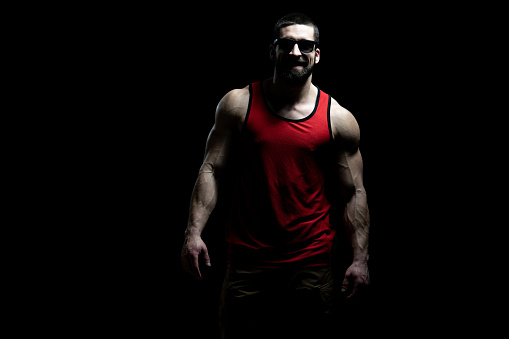 Portrait of a Young Man With Sunglasses and Undershirt Flexing Muscles - Isolate on Black Blackground - Copy Space