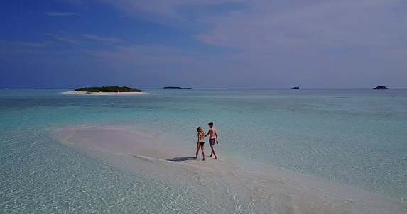 A panoramic view of a couple walking on the sandy beach in Rasdhoo Island, the Maldives