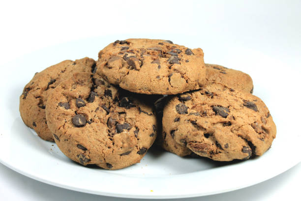 istock Closeup of chocolate chip cookies inside white plate on white background 1440980624