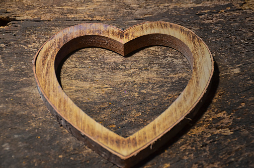 A photo of a wooden heart frame on a wooden surface, love and Valentine's Day concept