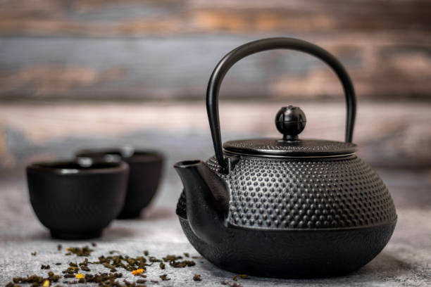 istock Black teapot with some green tea on the table 1440981413