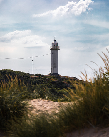 A vertical shot of the Subbe Lighthouse on a hill under a cloudy sky in Varberg, Sweden