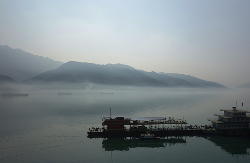 A peaceful scene with Changjiang River and mountains in the background on a foggy day