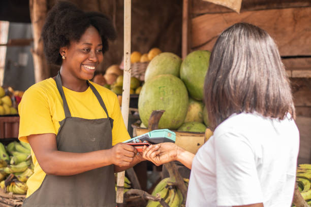 istock Black woman selling goods in a market using a pos device 1440982327