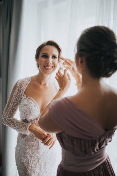 istock Bridesmaid helping the bride to get dressed for the wedding ceremony 1440985473