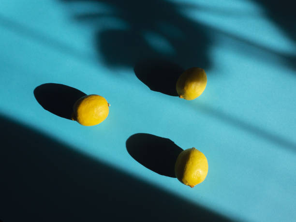 istock Top view of three fresh ripe lemons on a blue table under a bright sunlight 1440985708