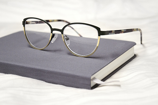 A closeup of glasses on the notebook on the white fabric