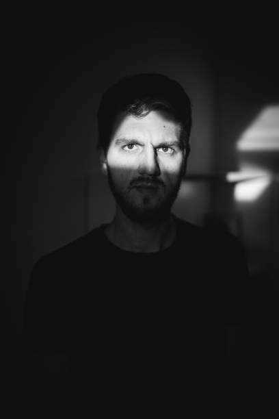 istock Grayscale shot of a handsome guy looking at the window with sun rays falling on his face 1440986225