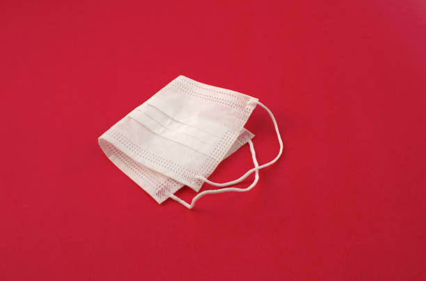 istock White mask on the side on a red surface. protective mask used in medicine worldwide. Vaccination, prevention, medical and healthcare concept. 1440988813