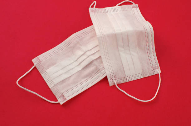istock White mask on the side on a red surface. protective mask used in medicine worldwide. Vaccination, prevention, medical and healthcare concept. 1440989033
