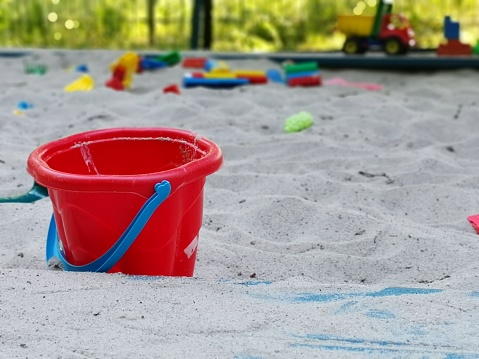 The closeup of toy beach bucket on the sand in the playground with copy space