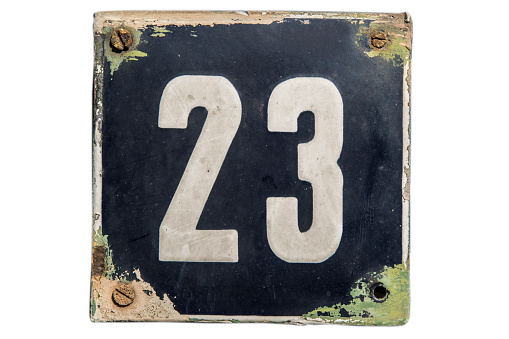 Weathered grunge square metal enameled plate of number of street address with number 23 isolated on white background