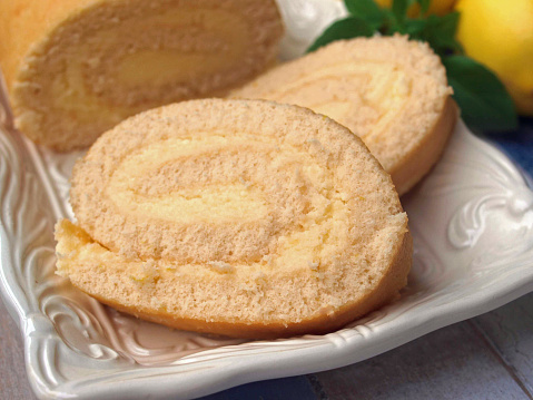 Homemade lemon swiss roll cake on a plate, lemon curd cake roll