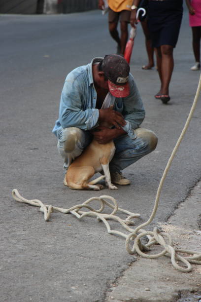 cuba - La Havane - August 6, 2019 -  a worker stops to kiss a stray dog ​​in the street