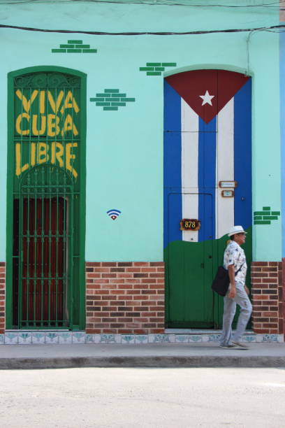 cuba - la havane - old havane -August 7, 2019\n two doors in the old town - one with the flag of cuba and one with the writing viva cuba libre and a passerby