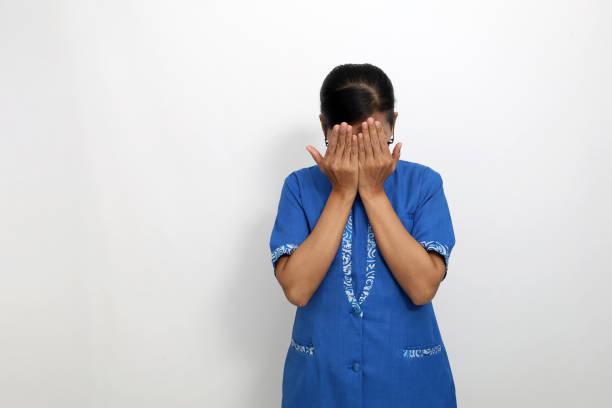 Stressed young asian woman standing while covering her face. Isolated on white with copyspace