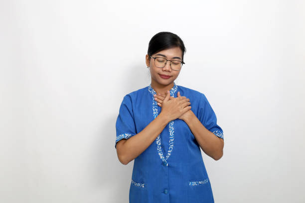 istock Relieved young asian woman standing while holding chest. Isolated on white background 1440996468