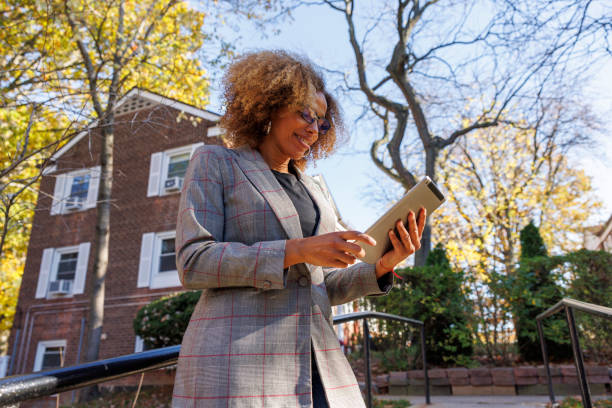 Smiling appraiser is checking her tablet while inspecting the front yard of the townhouse. stock photo