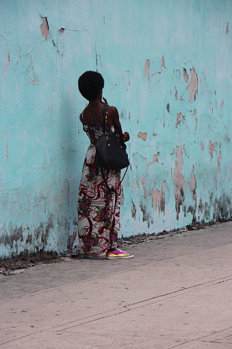Cuba - La Havane -street scene -  beautiful lady waiting along a blue wall