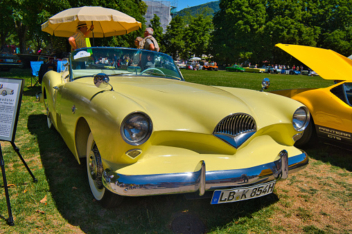 Baden-Baden, Germany - 10 July 2022: light yellow 1954 Kaiser Darrin cabrio roadster is parked in Kurpark in Baden-Baden at the exhibition of old cars \