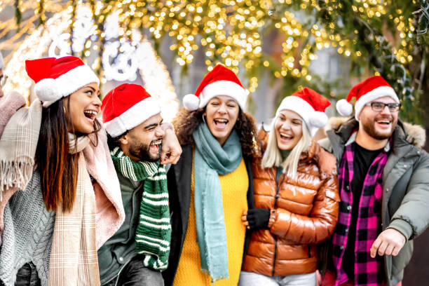 istock Young friends group walking under Christmas tree decorations - Winter life style concept with trendy happy people wearing red santa hats while having fun holidays together outside - Warm bright filter 1441006907