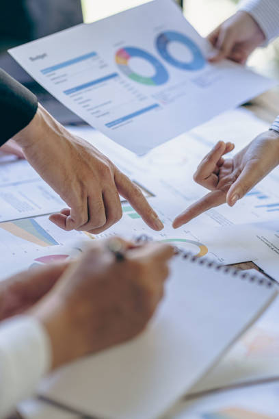 istock Young colleagues working together on startup projects in modern office Businessman brainstorming analyzing financial graphs calculating company earnings Vertical photo, flare 1441007958