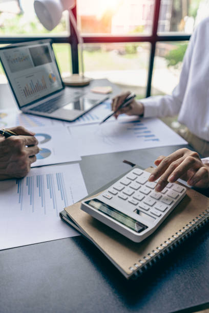 istock Young colleagues working together on startup projects in modern office Businessman brainstorming analyzing financial graphs calculating company earnings Vertical photo, flare 1441008533