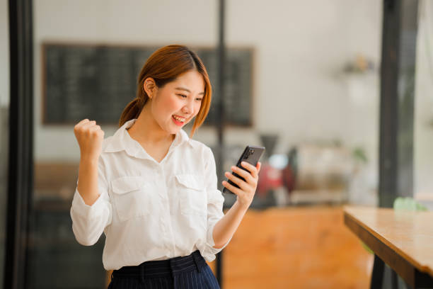 excited asian woman talking on the phone in a dating app. closeup happy joyful feeling reading good news on phone - winners podium audio imagens e fotografias de stock