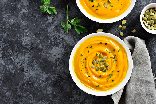 Pumpkin puree in bowl over dark stone background with free text space. Healthy diet food concept. Top view, flat lay