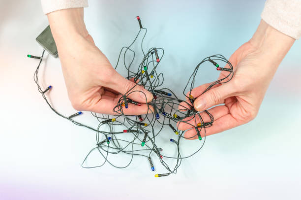 istock Women's hands hold tangled Christmas tree garland. Stress before celebration. old tree decorations 1441015617