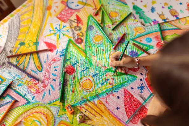 istock Creative girl using a colored pencil to draw a Christmas theme on the paper 1441016570
