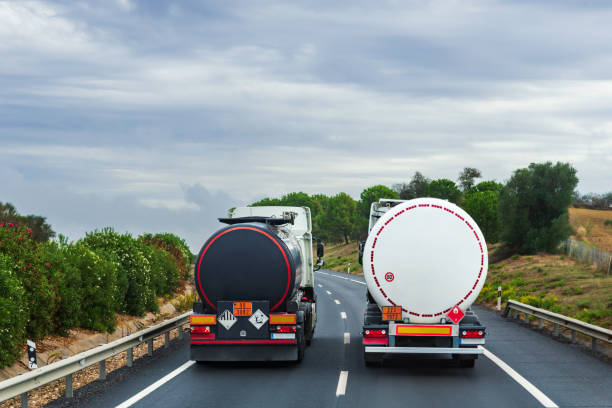 dos camiones cargados de mercancías peligrosas, uno de líquidos contaminantes y el otro de gases inflamables, paralelos en la carretera en el momento de los adelantamientos. - overtake fotografías e imágenes de stock