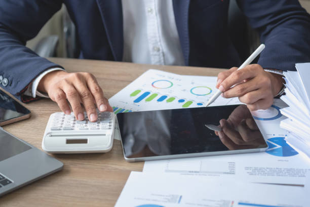 istock businessman use calculators and graph analysis computer laptop tablets to plan marketing strategies and make profitable investments for the company. 1441025866