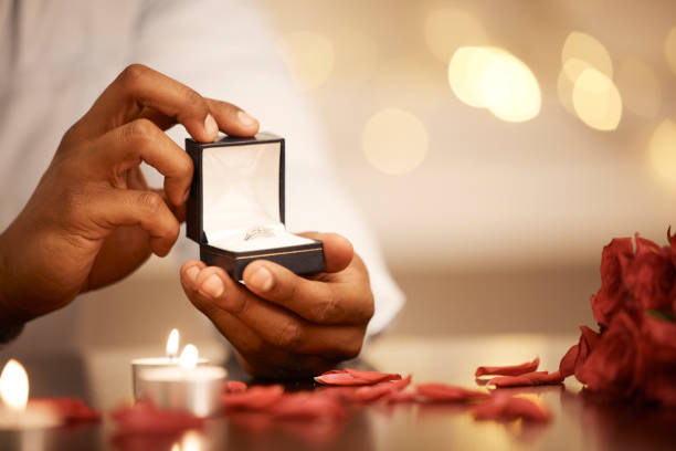 fidanzamento, gioielli e proposta con fede nuziale per regalo, celebrazione o annuncio durante un appuntamento romantico. salva la data, ama o regala con gioielli con diamanti per impegno o sorpresa - men african descent giving flower foto e immagini stock