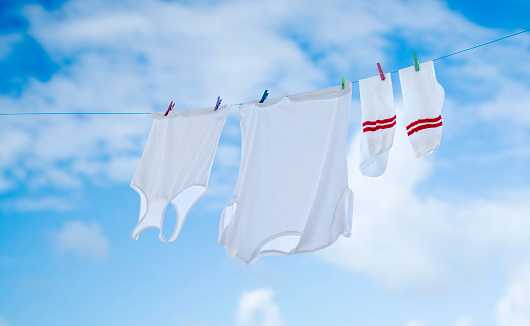 A housewife removes dry laundry from a clothesline that was drying in the backyard of the house.